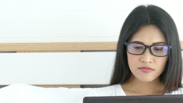 ベッドの上の美しいアジアの女性が彼女のラップトップを使用してウェブを閲覧するには — ストック動画
