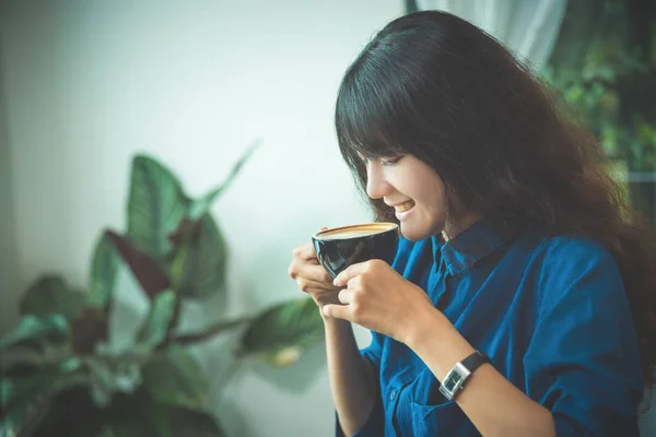 Schöne junge Frau trinkt Kaffee und lächelt — Stockfoto