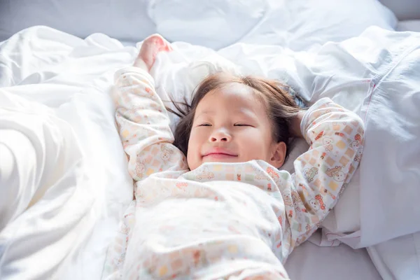 Liten flicka vaknar upp på sängen i tidig morgon — Stockfoto