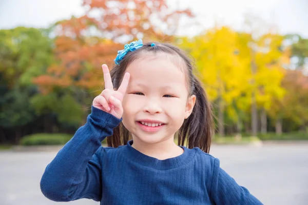 Girl doing gesture victory hand with smiles in park — Stock Photo, Image