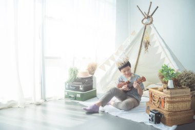 Ukulele evde çadır önünde oynayan genç Asyalı çocuk