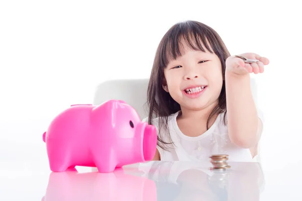 小亚洲女孩显示她的钱与粉红色的小猪银行的白色背景 — 图库照片