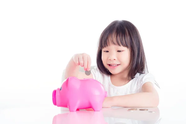 Маленькая Азиатская Девочка Кладет Монетку Розовый Копилку Белом Фоне — стоковое фото