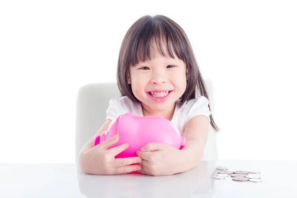 白地にピンクの貯金を抱き締める小さなアジアの女の子 — ストック写真