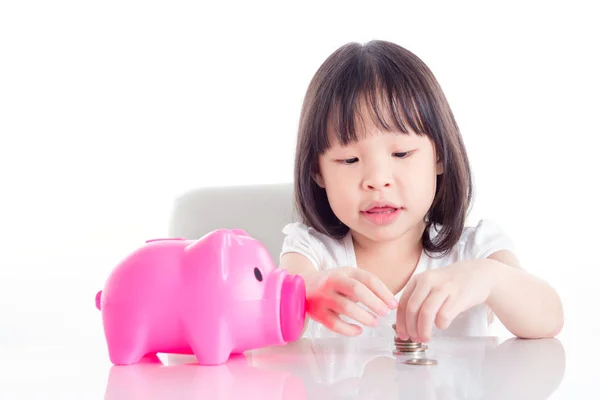 小亚洲女孩计数粉红色的小猪银行在白色背景硬币 — 图库照片