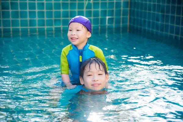 Barn i badkläder leker i poolen — Stockfoto