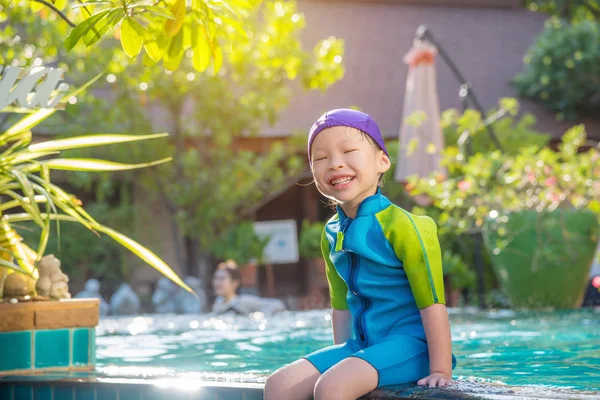 Flicka klädd simma kostym sitter och ler vid pool — Stockfoto