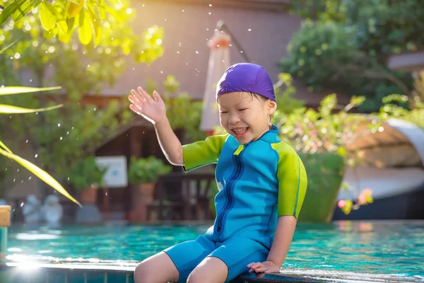 Flicka klädd simma kostym sitter och ler vid pool — Stockfoto