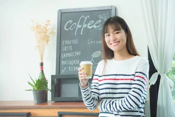 Vrouw permanent en holding koffiekopje en glimlach — Stockfoto