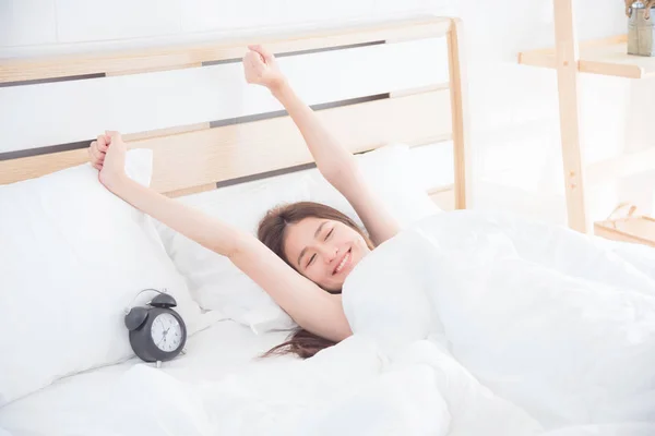 Vrouw die zich uitstrekt op bed in de ochtend — Stockfoto