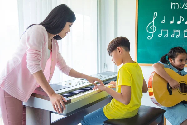 教室で先生の音楽キーボードを再生アジア少年 — ストック写真