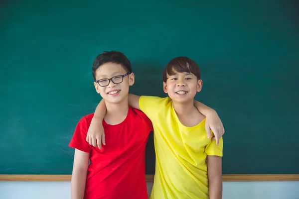 二人の若いアジア学生立っていると黒板の前で笑顔 — ストック写真
