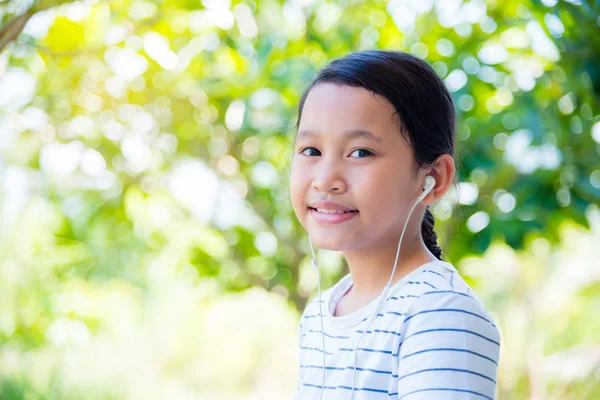 美丽的亚洲女孩戴着耳机和微笑在公园里 — 图库照片