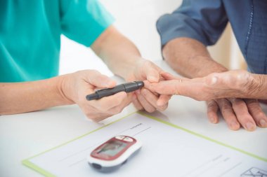 Hemşire eller Lancet kontrol hastanın kan şekeri için kullanma