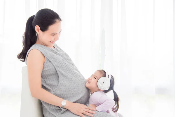 Ligirl hoofdtelefoon dragen en lachend met haar moeder — Stockfoto