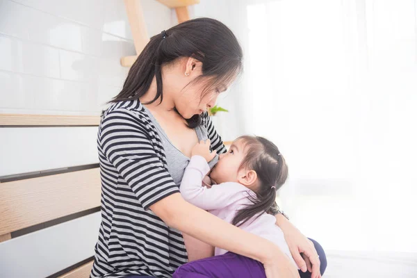 Женщина кормит свою дочь грудью дома — стоковое фото