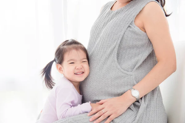 Meisje luisteren geluid uit haar zwangere moeders buik — Stockfoto