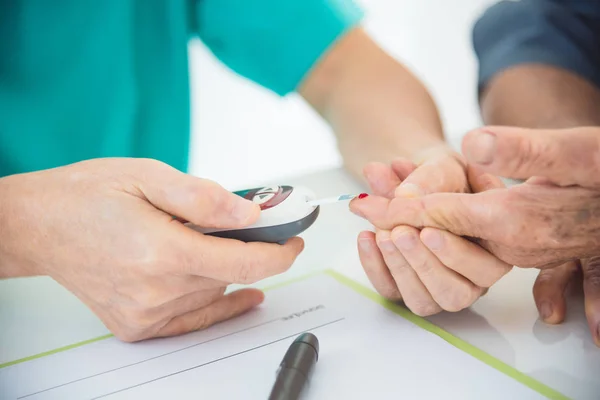 Zdravotní sestry ruce používající glukometr na prst pacienta — Stock fotografie