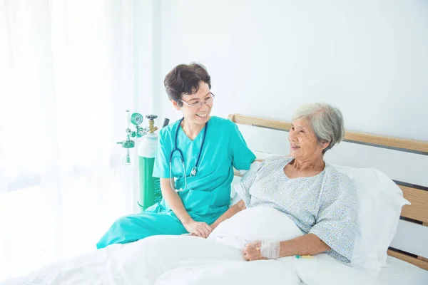 シニアの女性患者が看護師を訪ねてくる笑みを浮かべて — ストック写真