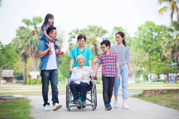 Paciente feminina sênior sentada em cadeira de rodas com sua família — Fotografia de Stock
