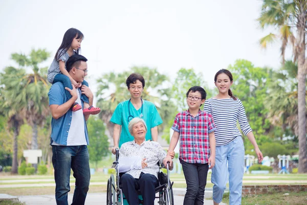 Senior vrouwelijke patiënt zittend op rolstoel met haar familie — Stockfoto