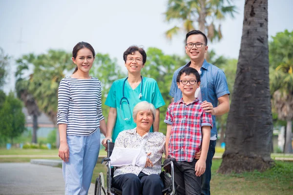 Senior vrouwelijke patiënt zittend op rolstoel met haar familie — Stockfoto