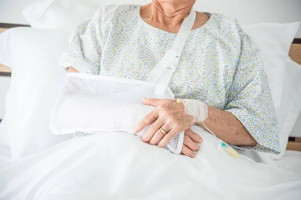 ベッドの上に座って先輩患者の腕の骨折 — ストック写真
