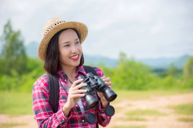 Güzel Asyalı kadın kuşları görmek için dürbün kullanıyor. 