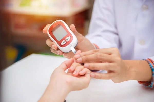 Mani del farmacista che controlla lo zucchero nel sangue del paziente tramite glucometro — Foto Stock
