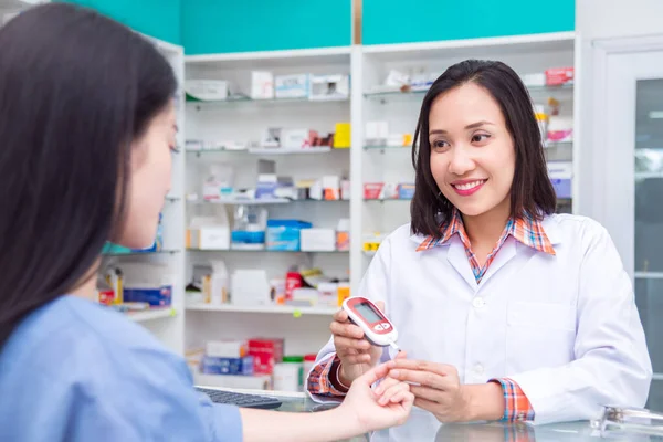 Piękny farmaceuta sprawdzający stężenie cukru we krwi pacjenta przez glukometer — Zdjęcie stockowe