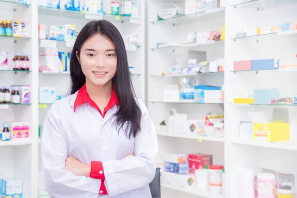 Krásný asijský lékárník stojící v lékárně a usmívající se — Stock fotografie