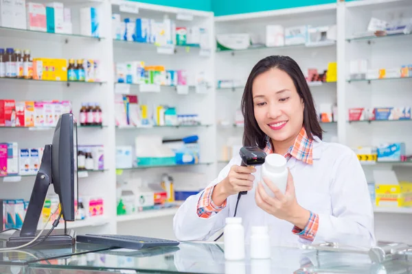 Piękny aptekarz stojący w aptece i skanujący kod kreskowy na butelce — Zdjęcie stockowe