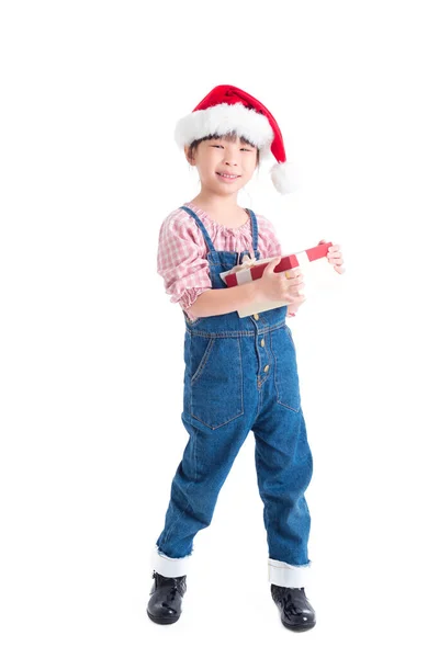 Pleine longueur de petite fille portant santa claus chapeau tenant boîte cadeau et sourires — Photo