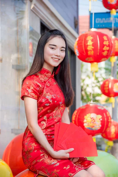 Schöne asiatische Frau in traditionellem chinesischem langen Kleid mit rotem Umschlag und lächelt — Stockfoto