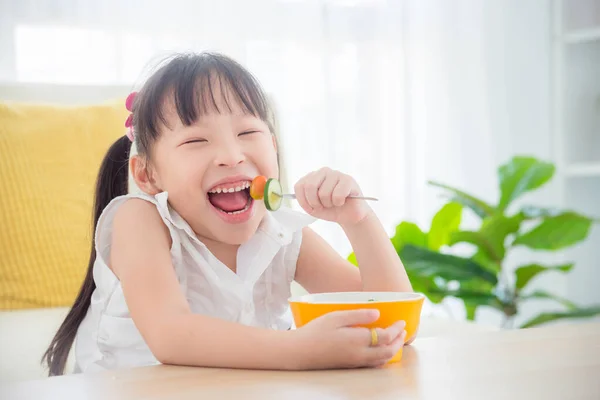 Little asian girl eating salad at home. — Stock Photo, Image