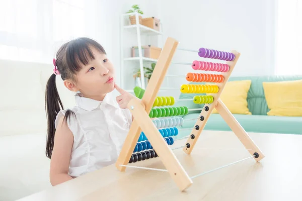 Malá asijská dívka hraje barevné dřevěné abacus v obývacím pokoji — Stock fotografie