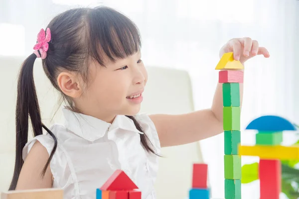 Evde renkli tahta bloklar oynayan küçük bir kız. — Stok fotoğraf