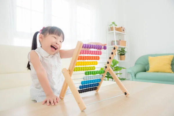 Pequeña chica asiática jugando abaco de madera colorido en la sala de estar — Foto de Stock