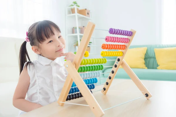 Malá asijská dívka hraje barevné dřevěné abacus v obývacím pokoji — Stock fotografie