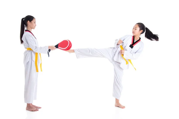 Two young asian girls having taekwondo training ,one girl kicking while other one girl holding kick target — Stock Photo, Image