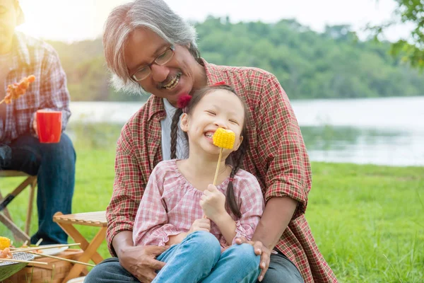 Little asian girl enjoy with eating grilled corn with her grandfather — Stock Photo, Image