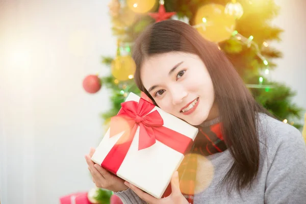 Mooi jong aziatisch meisje zitten op de vloer in de woonkamer en het houden van geschenkdoos en glimlacht — Stockfoto