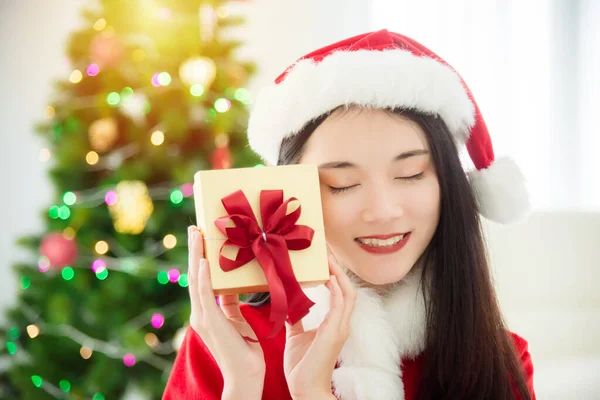 Mooie Aziatische vrouw in Santa Claus kostuum met hoed houden geschenkdoos — Stockfoto