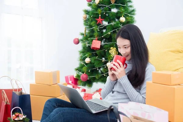 Mooi jong aziatisch meisje zitten op de vloer in de woonkamer en met behulp van notebook computer voor winkelen — Stockfoto