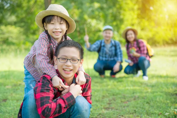 Happy siblings smiling with their father and mother sitting in background. — Stock Photo, Image