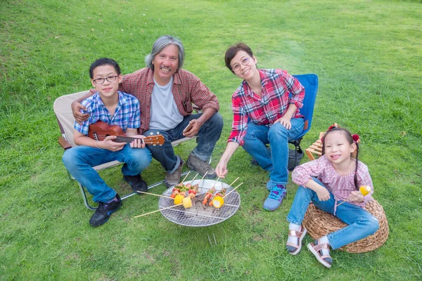 Group of asian family grilling barbecue and sweet corn on stove
