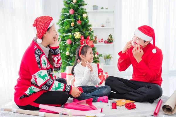 Gelukkig aziatisch familie zitten en verpakt kerstcadeaus samen in de woonkamer — Stockfoto