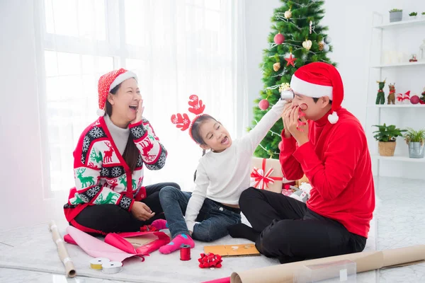 Gelukkig aziatisch familie zitten en verpakt kerstcadeaus samen in de woonkamer — Stockfoto
