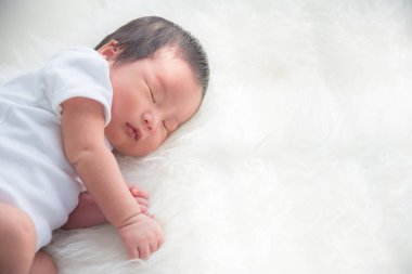Küçük yeni doğmuş bebek beyaz yatakta uyuyor. 