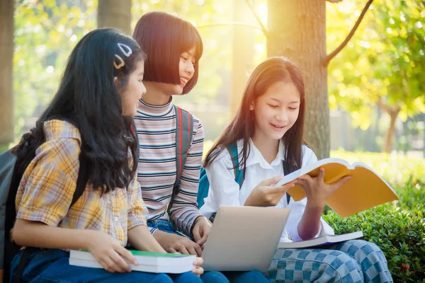 Студентка-підліток сидить у парку і використовує ноутбук для домашнього завдання — стокове фото